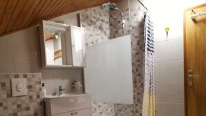 A modern bathroom with a shower, toilet, sink, and mirror.