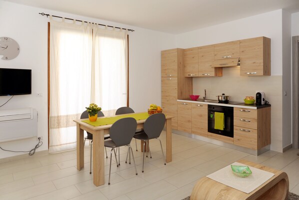 Une cuisine moderne avec des meubles en bois, une table à manger avec des chaises et un téléviseur fixé au mur.