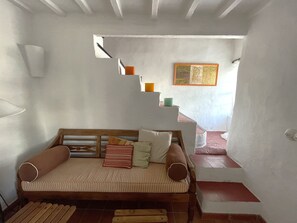 A cozy room with a wooden sofa, a small staircase, and a framed picture on the wall. - Charming traditional house (Fornells)