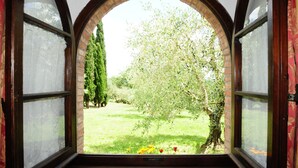 Een kamer met een rondboogvenster met uitzicht op een tuin met bomen en bloemen.