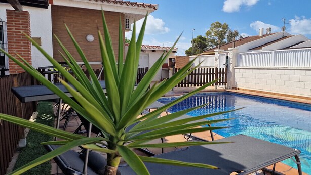 A swimming pool with a white fence, a brick wall, and a wooden deck with chairs and a plant. - "Josef"@MARISOL: 490m to the beach, private pool, A/C, WiFi, dog beach. (Riumar)