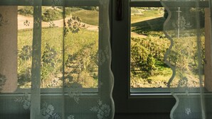 Een raam met bloemenmotieven en uitzicht op een groen landschap.
