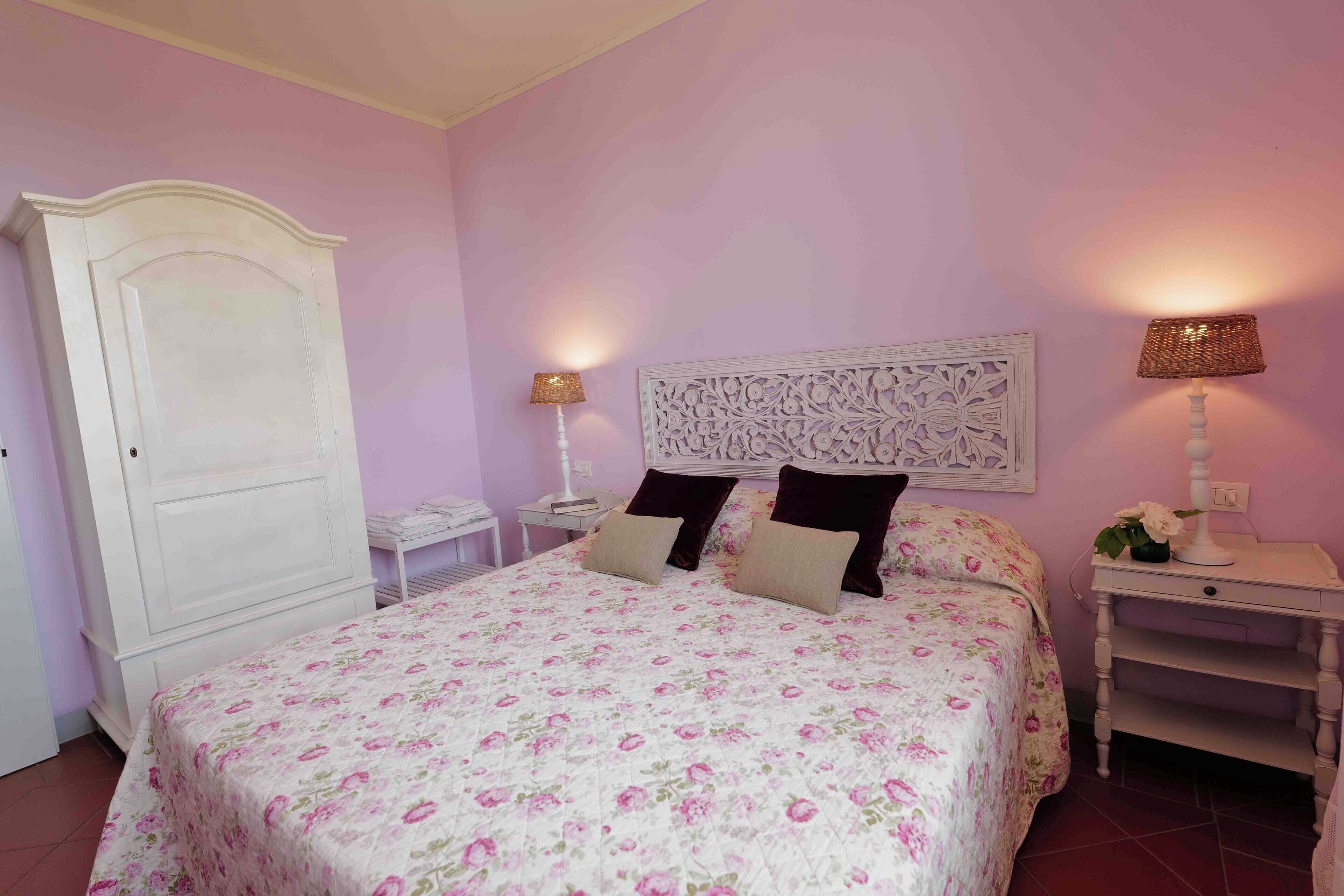 A bedroom with a bed, nightstands, a dresser, and a decorative headboard.
