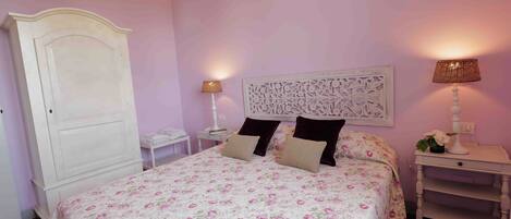 A bedroom with a bed, nightstands, a dresser, and a decorative headboard.