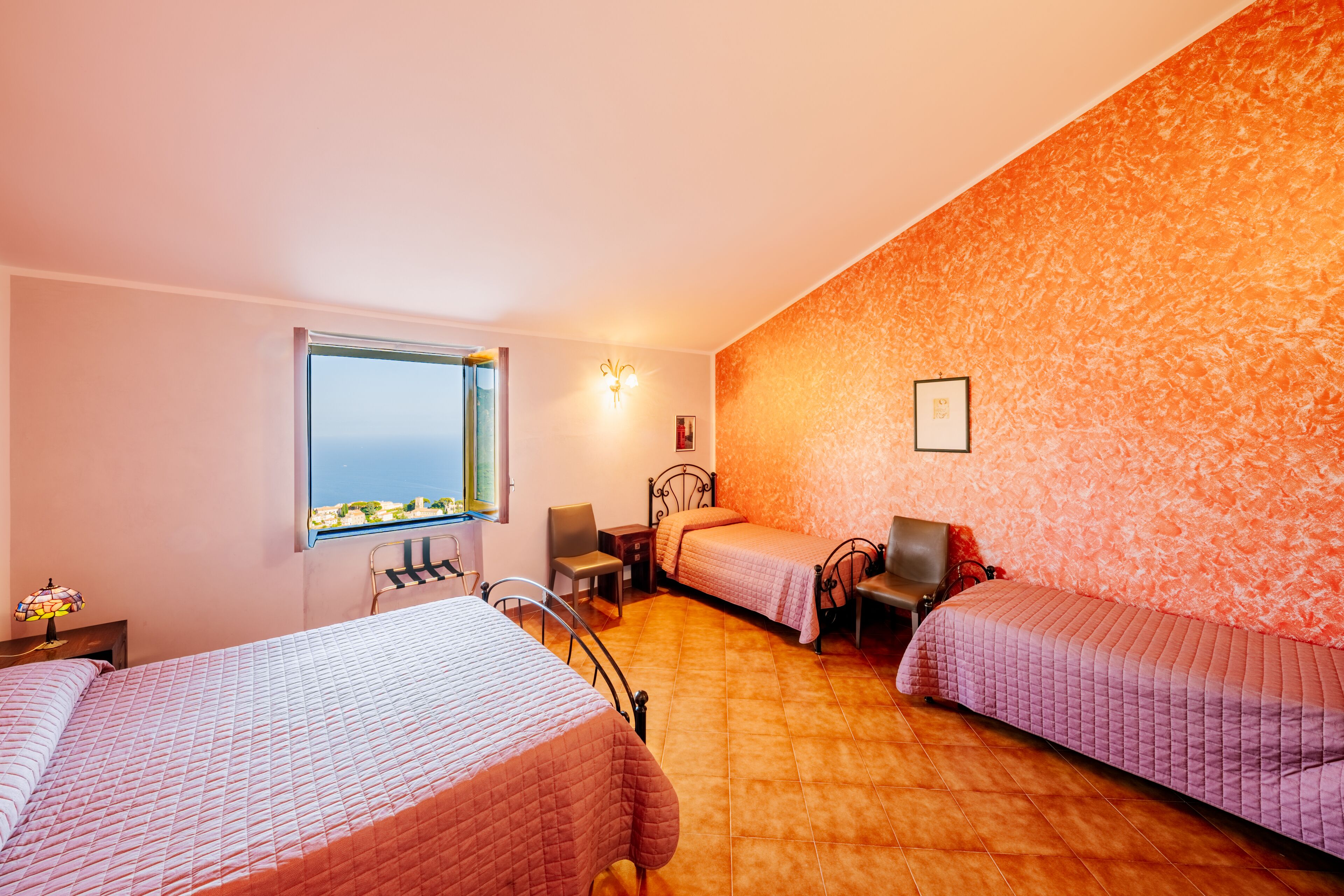 Une chambre d’hôtel avec deux lits, une fenêtre donnant sur un paysage agréable, une lampe fixée au mur et une chaise.