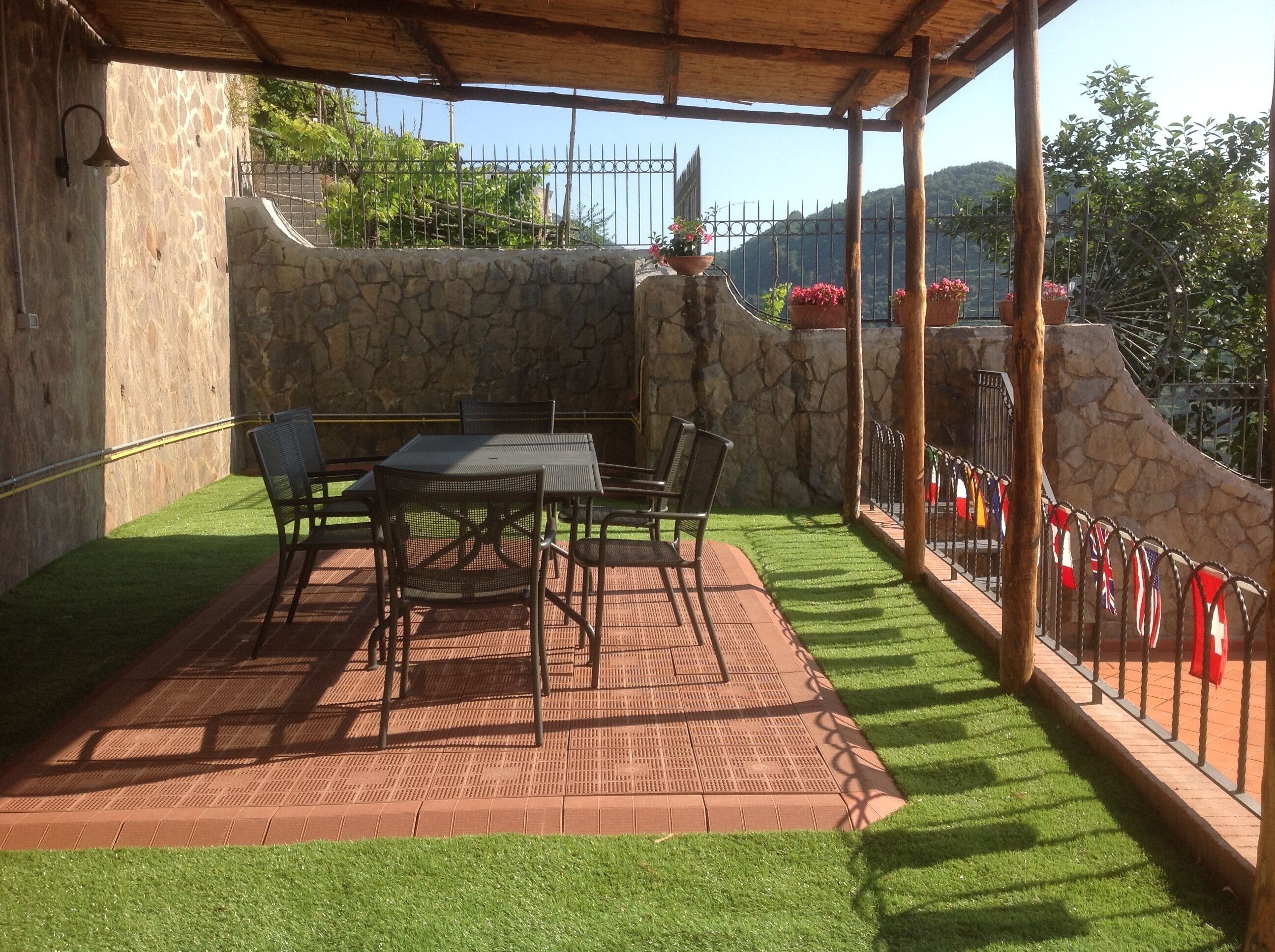 Une terrasse extérieure avec un mur en pierre, un espace salon abrité et une vue sur un paysage montagneux.
