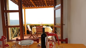 A dining area with a table set for two, a bottle of wine, and a pitcher with a strawberry design. - 1-bedroom apartment 2/3 people in quiet location (Palinuro)