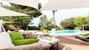 Eine Außenterrasse mit Pool, Liegestühlen und einem Esstisch.