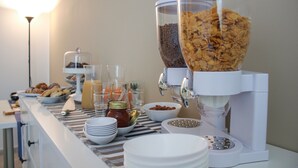 A breakfast buffet setup with cereal dispensers, a variety of food items, and serving utensils. - Belice Rooms (Salemi)