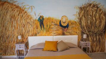 Un dormitorio con una cama grande, dos mesitas de noche y un mural que representa un campo de trigo con dos figuras.