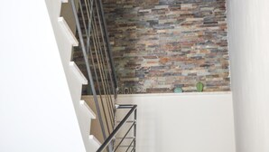 A staircase with a metal railing and a wall with a textured, multicolored stone pattern. - Belice Rooms (Salemi)