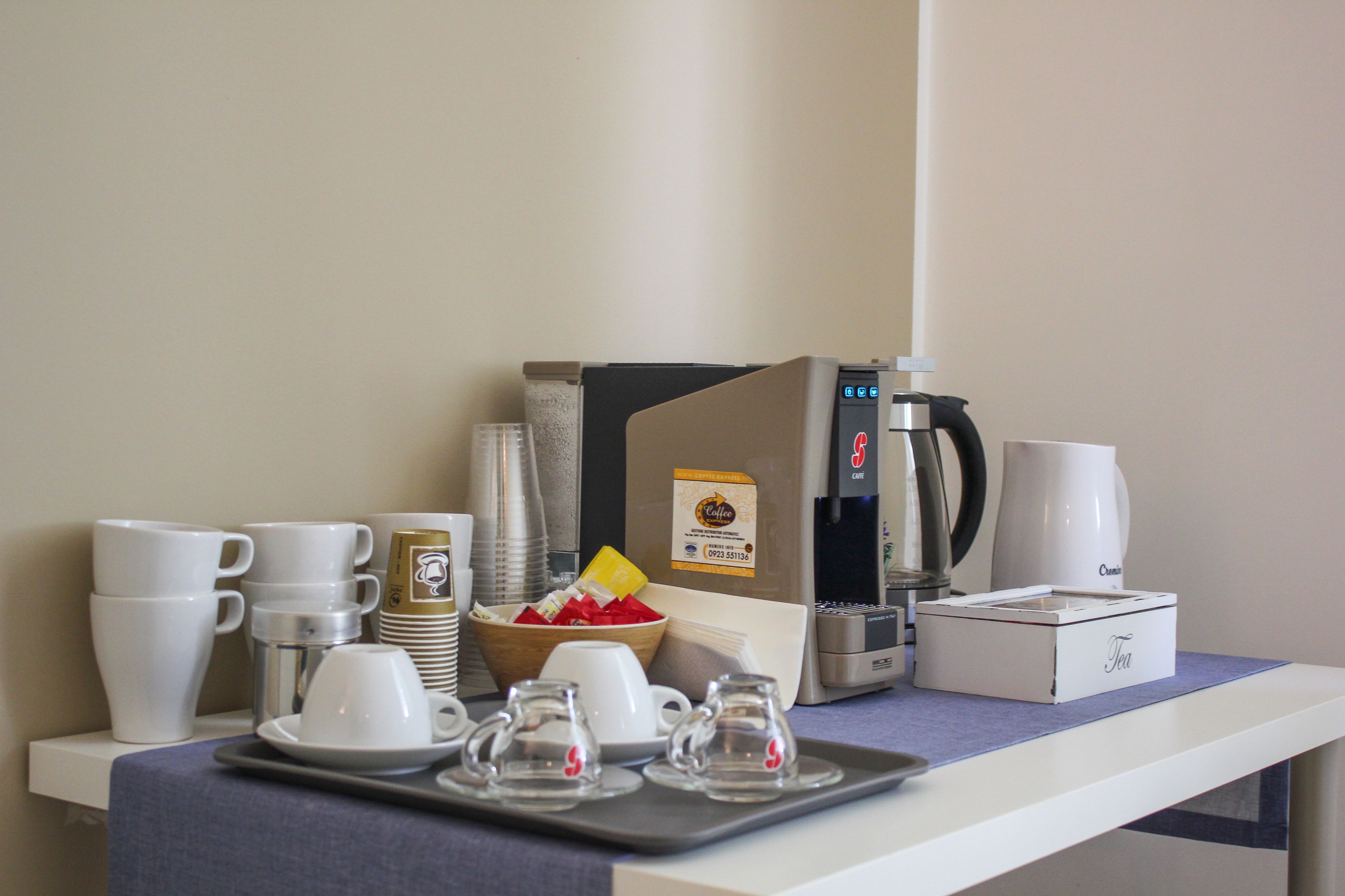 Un buffet de petit-déjeuner proposant du café et du thé, avec une machine à café, des tasses et une boîte à thé.