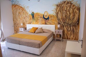 A bedroom with a large bed, two bedside tables, a nightstand, and a wall mural of a wheat field. - Belice Rooms (Salemi)