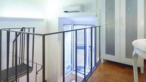 A room with a staircase, a white wardrobe, and a window with blinds. - Duplex Apartment (Roma)