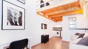 A room with a loft bed, a desk, a chair, a washing machine, and a couch. - Duplex Apartment (Roma)