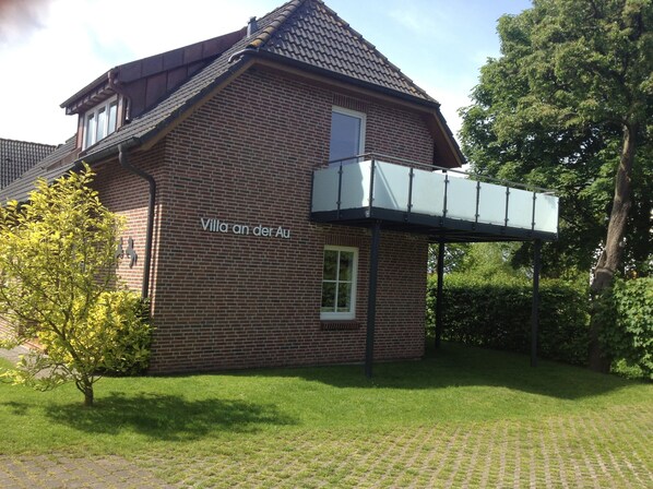 A brick building with a balcony and a sign that reads "Villa an der Au".