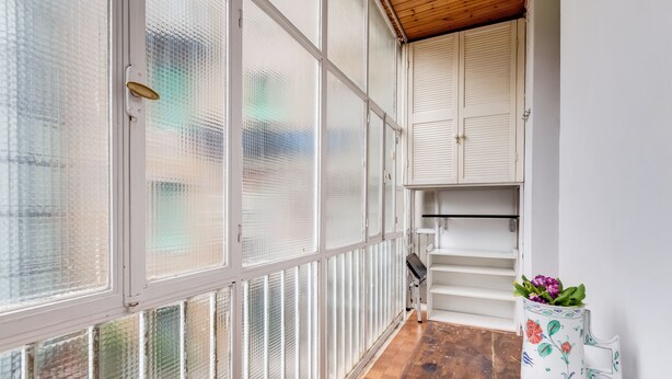 A narrow corridor with frosted glass doors, a wooden floor, and a white bench.