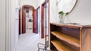 A hallway with a wooden door, a mirror, and a shelf with a vase.