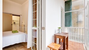 A room with a bed, a small table, and a window with a view.