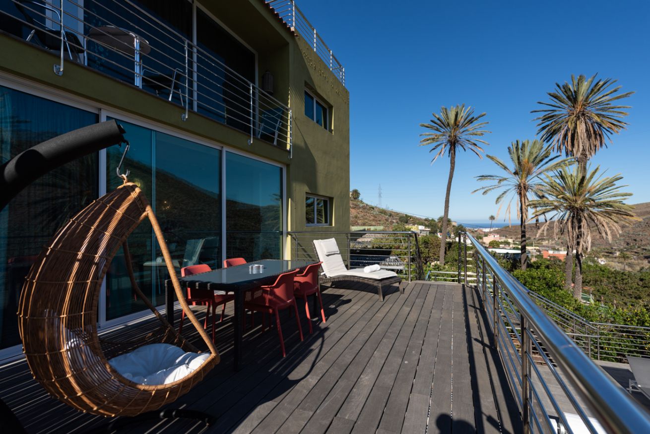 Eine Terrasse mit Gartenmöbeln, einem Hängesessel und Meerblick.