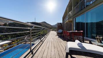 Una terraza soleada con piscina, sillas de descanso y una mesa con sillas.
