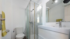 Ein modernes Badezimmer mit einer gläsernen Duschkabine, einer weißen Toilette und einem weißen Waschbecken mit Spiegel darüber.