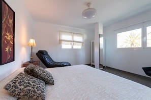 Een slaapkamer met een bed, een stoel, een lamp en een raam.