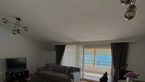 Ett modernt vardagsrum med en soffa, ett soffbord, en tv och ett matbord med en vas.