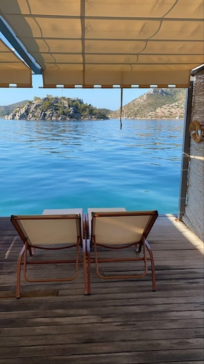A wooden deck with two chairs facing a body of water and a rocky island in the distance. - Hotel Melisa (Marmaris)
