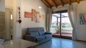 Uma sala de estar com sofá, mesa e varanda com vista.