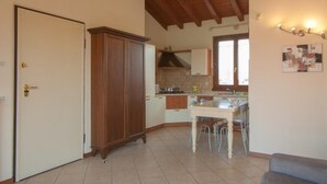 Cozinha compacta com armário de madeira, mesa de jantar com cadeiras e janela que oferece luz natural.