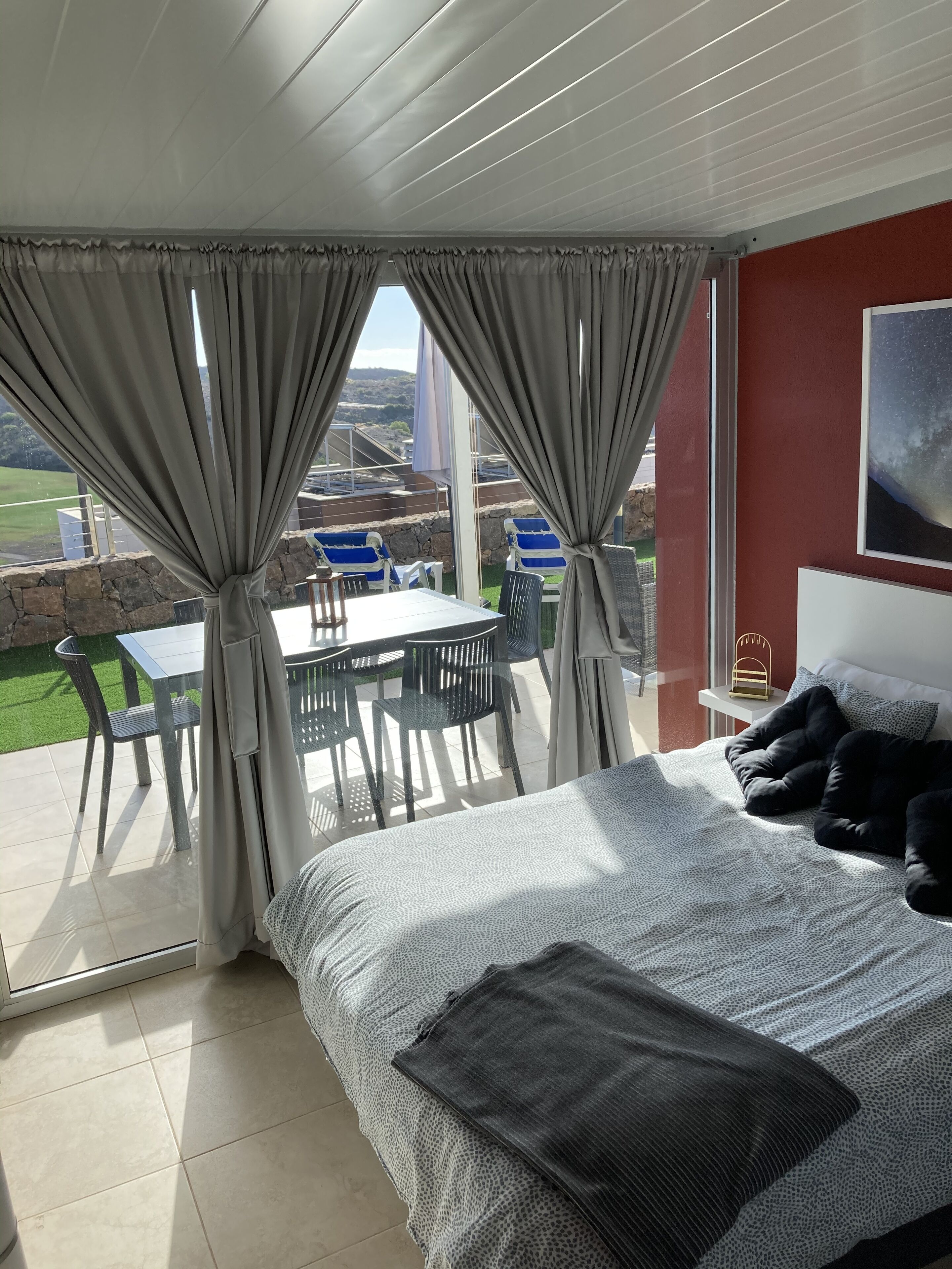 Un dormitorio con una cama grande, vistas al exterior y un comedor con sillas y una mesa.