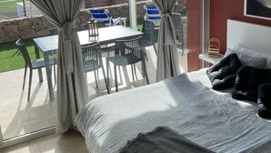 Un dormitorio con una cama grande, vistas al exterior y un comedor con sillas y una mesa.