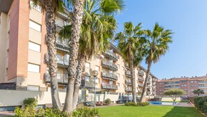 A multi-story residential building with balconies, a swimming pool, and palm trees. - 2P53 - Cozy apartment for 4 people with pool located near the center and the beach of Fenals (Lloret de Mar) (Lloret de Mar)
