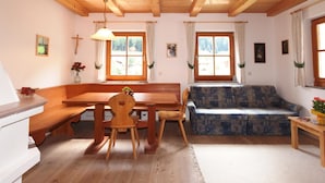 Ein gemütliches Zimmer mit einem Holzesstisch, einer Bank und einem gemusterten Sofa.