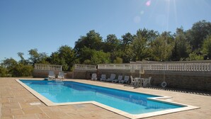 A rectangular swimming pool with a stone deck, surrounded by lounge chairs and umbrellas. - Vacation Home Il Rigattiere private pool, nature, absolute relaxation (Gualdo, Macerata)