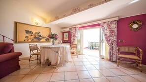 A dining area with a table, chairs, and a vase of flowers. There is a sofa and a bench in the room.