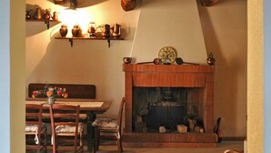 A rustic interior with a wooden ceiling, a fireplace, a dining table with chairs, and shelves with decorative items. - Casa Afra, nestled in the peaceful hills near Lucca, with breathtaking views (Pescaglia)