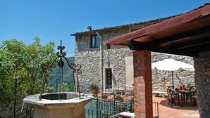 A stone building with a rustic roof, outdoor seating area, and a decorative metal structure. - Casa Afra, nestled in the peaceful hills near Lucca, with breathtaking views (Pescaglia)