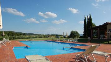 Ein Schwimmbecken mit Liegestühlen und einer Pergola.