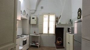 A compact kitchen with white cabinets, a gas stove, a microwave, and a small window. - Casa PORTATERRA, Antica Dimora for a peaceful stay in the heart of Salento (Scorrano)