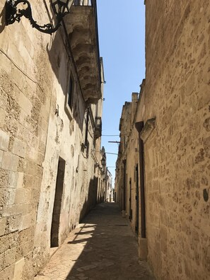 A narrow street with stone buildings, a clear sky, and a cobblestone path.