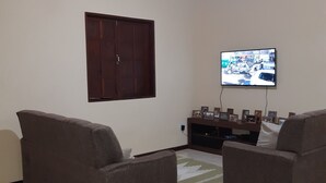 A living room with two sofas, a television mounted on the wall, a wooden ceiling, and a tiled floor. - São Roque House in Paraty (São Roque)