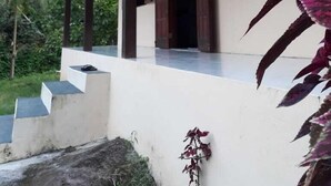 A covered outdoor area with a wooden roof, a white wall, and a small plant with purple leaves. - São Roque House in Paraty (São Roque)