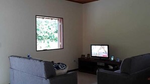 A living room with two sofas, a television, and a ceiling fan. - São Roque House in Paraty (São Roque)