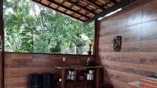 A kitchen area with a wooden counter, two stools, and a hanging lantern. - São Roque House in Paraty (São Roque)