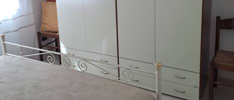 Un dormitorio con una cama, un armario, una silla y una mesita.