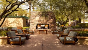 An outdoor patio with stone walls, a fire pit, and multiple seating areas with chairs.