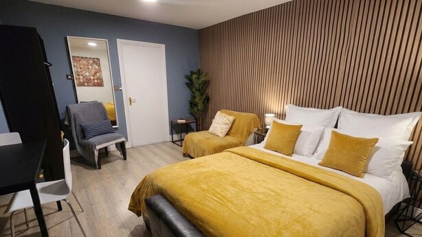A bedroom with a bed, bedside tables, a desk, and a chair. - Dodi Apartments (London)