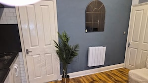 A room with a wooden floor, white doors, a radiator, and a potted plant. - Dodi Apartments (London)